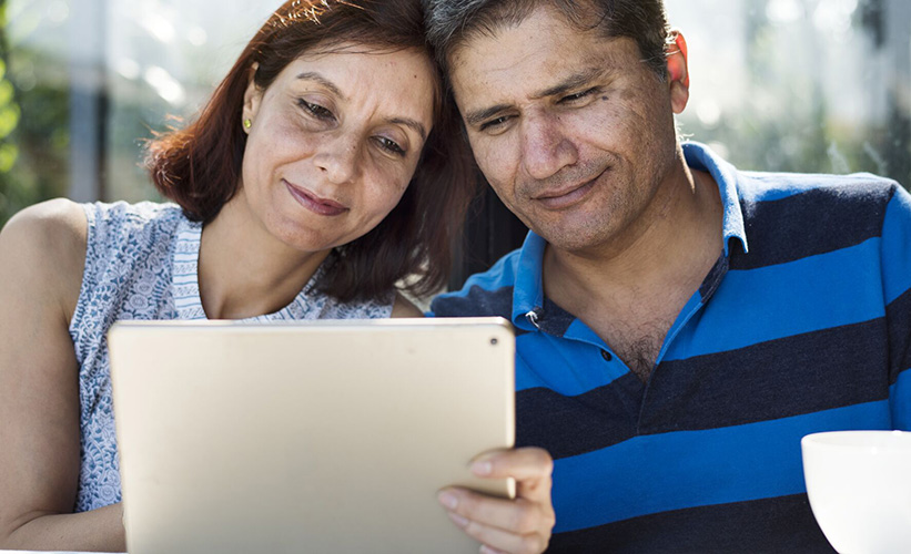 Couple sitting together and looking at a tablet