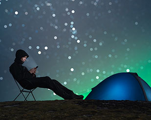 Man out camping with the northern lights in the background