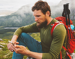 Man looking at this phone in the mountains