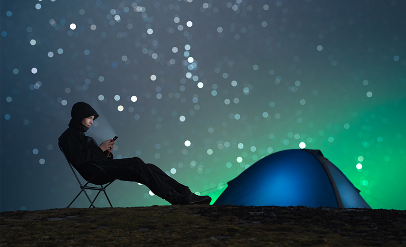 Man out camping with the northern lights in the background