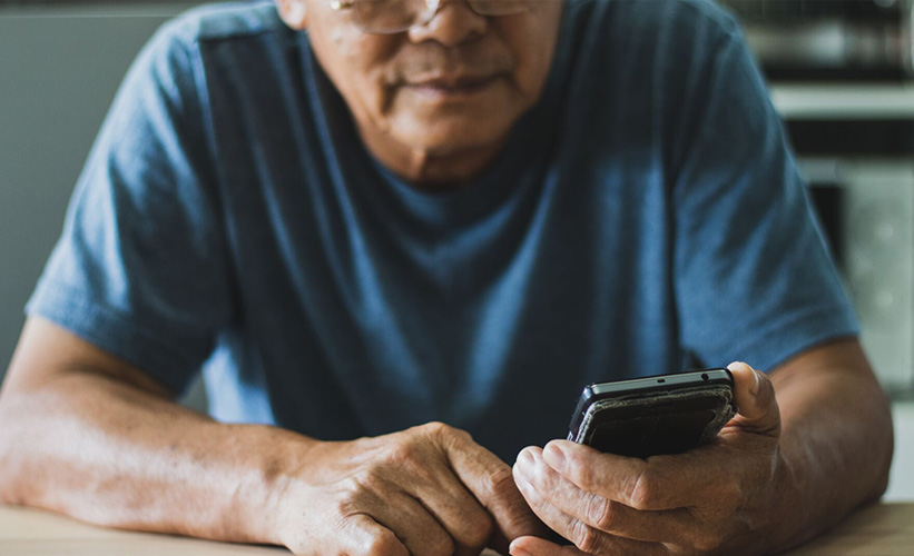 Older Asian man holding his phone