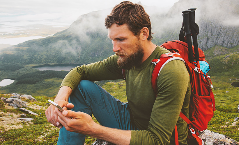 Man looking at this phone in the mountains