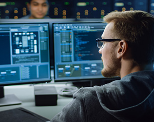 Man sitting in front of computer screens monitoring data