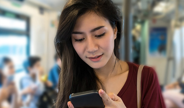 Asian woman looking at her phone at the subway