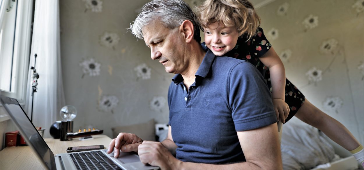 Employee working from home with his child looking over his shoulder