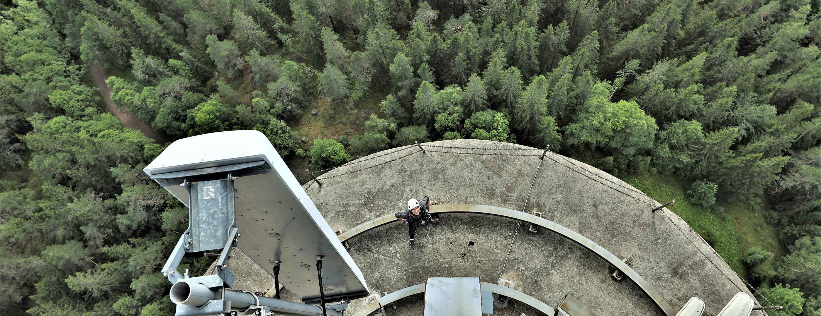 Person at the top of a base station surrounded by trees
