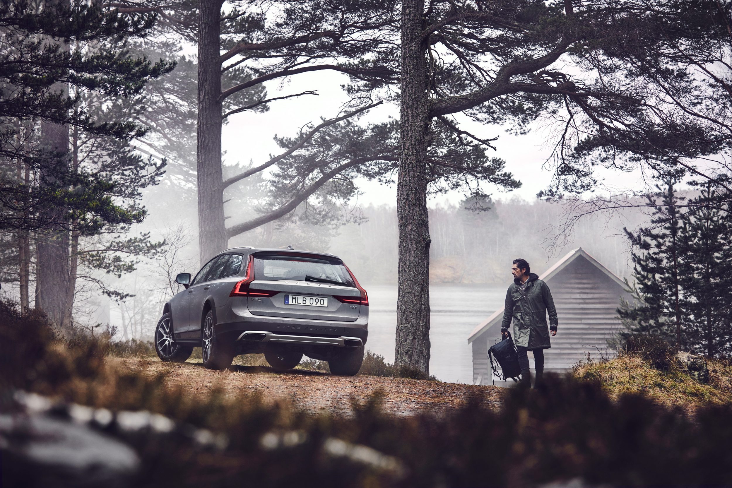 Man walking to a Volvo ca in the woods