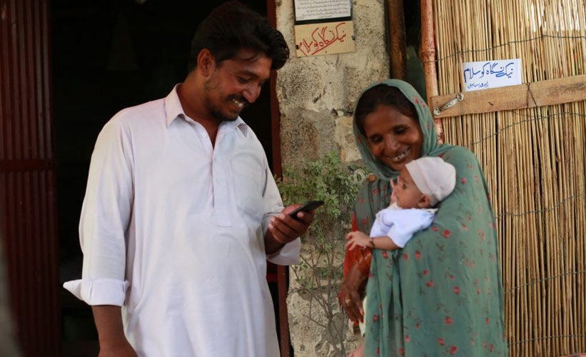 Couple holding a baby and registering the birth on their phone