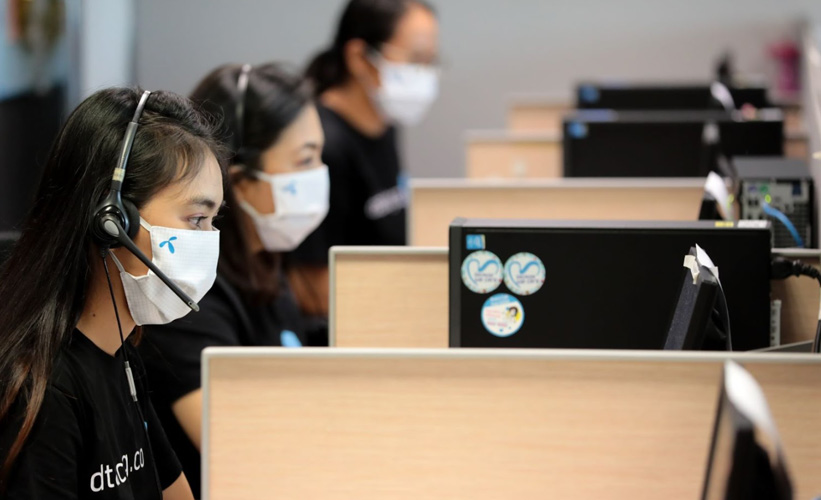 Three women wearing masks working at a call center in Thailand