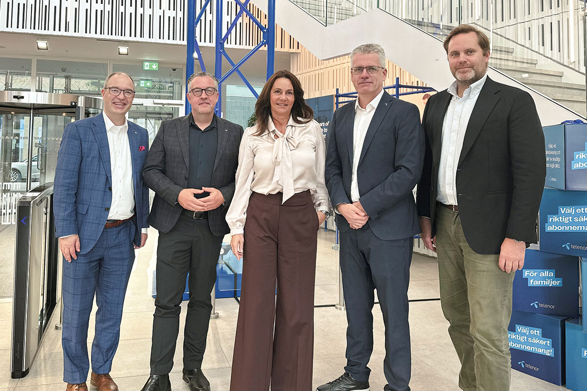 Gruppebilde innendørs med Telenor-reklame i bakgrunnen