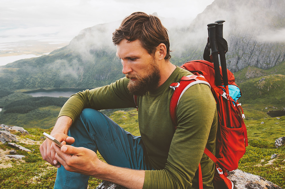 Man looking at this phone in the mountains
