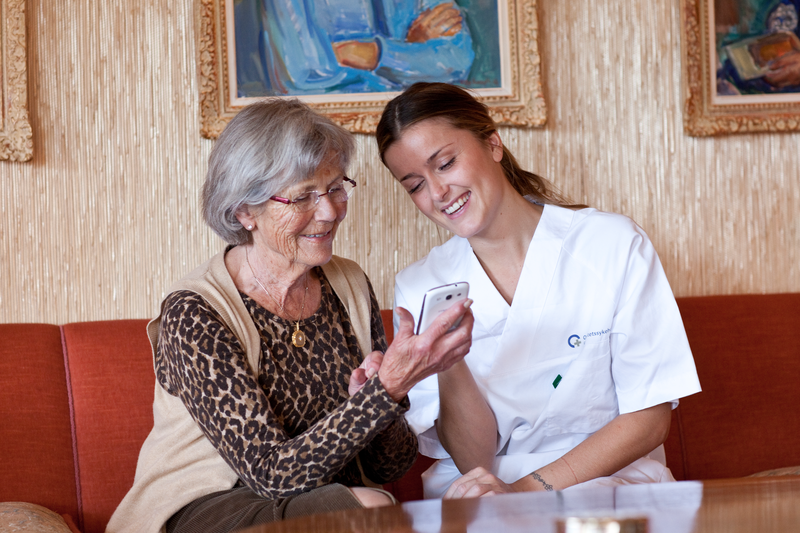Healthcare professional helping an elderly woman with her phone